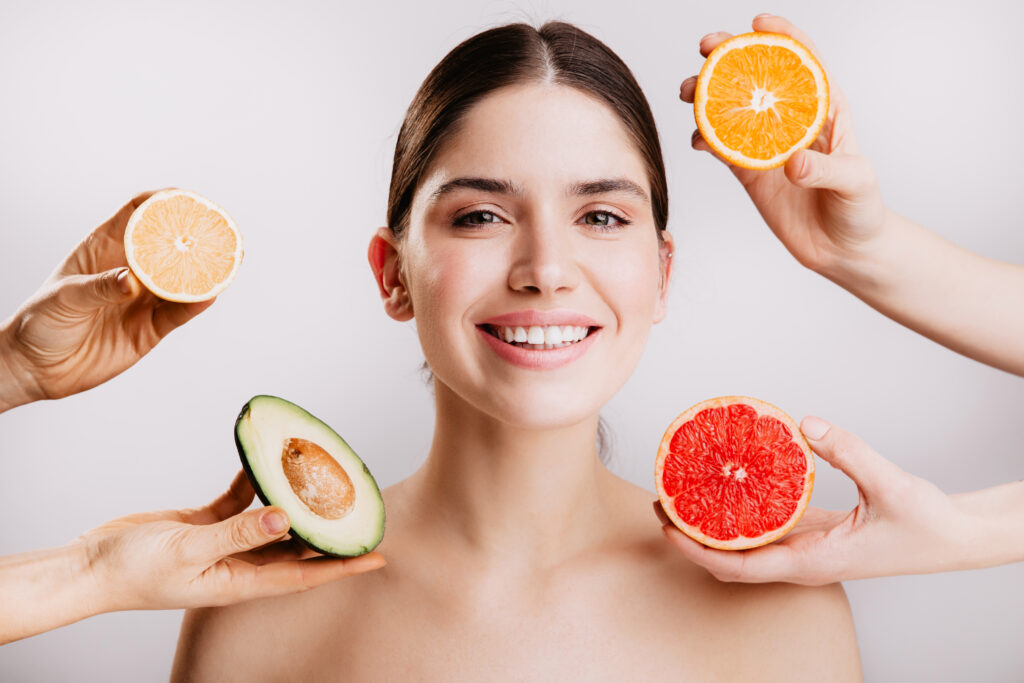 Healthy beautiful radiant skin of woman without makeup. Portrait of girl smiling against background of fruits.